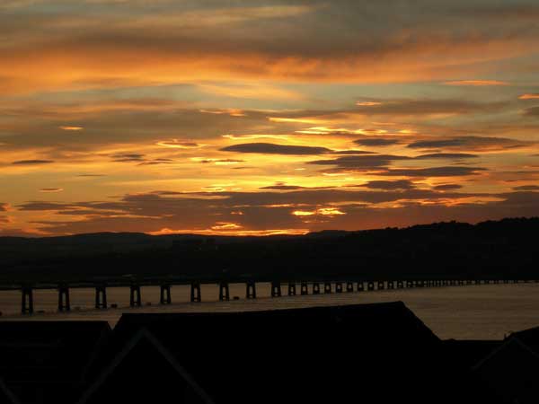 Soft yellow and orange light silhouette the Tay bridge